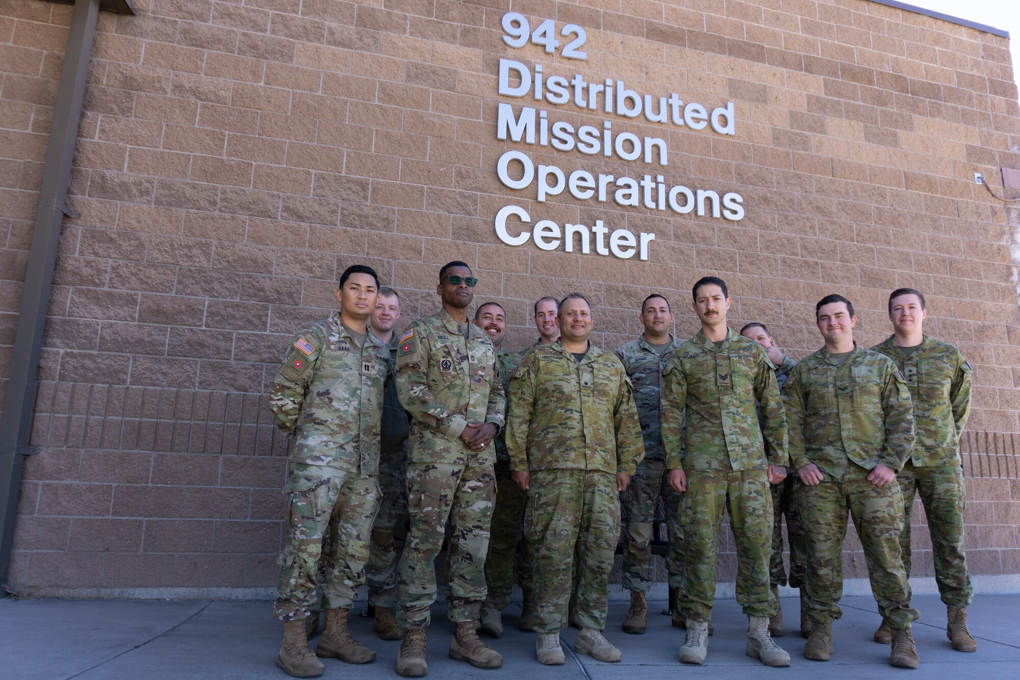 photo: military members stand in a group in front of building with wording “942 Distributed Mission Operation Center”