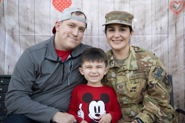 Two adults, one in uniform, flank a small boy wearing a Mickey Mouse shirt.