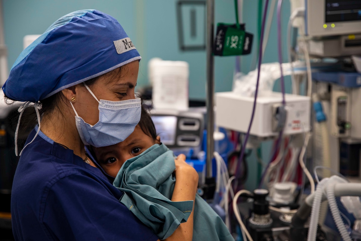 221117-N-VQ41-1020 CARTAGENA, Colombia (Nov. 17, 2022) Maria Nadales, a physician from Vama, Venezuala volunteering aboard hospital ship USNS Comfort (T-AH 20), holds a young Colombian patient before a cosmetic surgery aboard Comfort, Nov. 17, 2022. Comfort is deployed to U.S. 4th Fleet in support of Continuing Promise 2022, a humanitarian assistance and goodwill mission conducting direct medical care, expeditionary veterinary care, and subject matter expert exchanges with five partner nations in the Caribbean, Central and South America. (U.S. Navy photo by Mass Communication Specialist 2nd Class Ethan J. Soto)