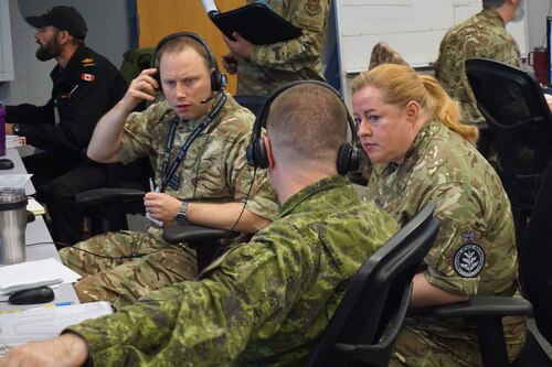 group of military members sitting and talking in an office environment