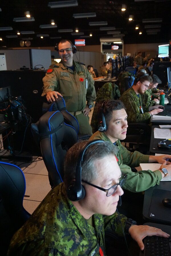 Royal Canadian Air Force forces participate in VIRTUAL FLAG: Coalition 23-1 at the 705th Combat Training Squadron, also known as the Distributed Mission Operations Center, at Kirtland Air Force Base, New Mexico, and distributed sites across four countries, Oct. 24 – Nov. 4, 2022. Exercise VFC serves as a train as you fight exercise by integrating the full spectrum of air, land, surface, space, and cyber warfighters in a virtual battlespace in joint and coalition environments; forces from the United States, United Kingdom, Australia, and Canada participated. (Security badges, documents, and screens were blurred for security reasons) (U.S. Air Force photo by Ms. Deb Henley)