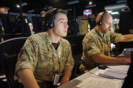 military members sit working at computers