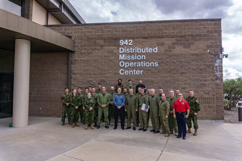 photo: military members stand in a group in front of building with wording “942 Distributed Mission Operation Center”