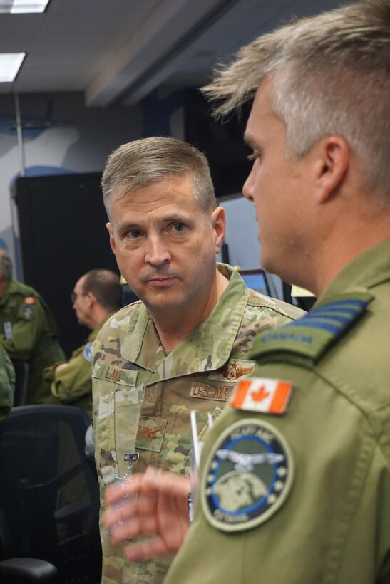 U.S. Air Force Col. Michael Lake, 505th Command and Control Wing vice commander, (left), listens to Royal Canadian Air Force distinguished visitor during VIRTUAL FLAG: Coalition 23-1 tour at the 705th Combat Training Squadron, also known as the Distributed Mission Operations Center, at Kirtland Air Force Base, New Mexico, Oct. 27, 2022. Exercise VFC serves as a train as you fight exercise by integrating the full spectrum of air, land, surface, space, and cyber warfighters in a virtual battlespace in joint and coalition environments; forces from the United States, United Kingdom, Australia, and Canada participated. (U.S. Air Force photo by Ms. Deb Henley)