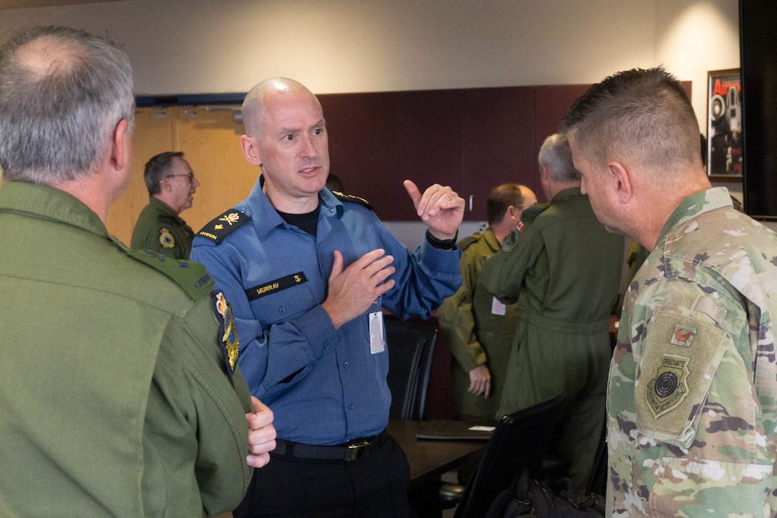 Military members standing talking in a conference room