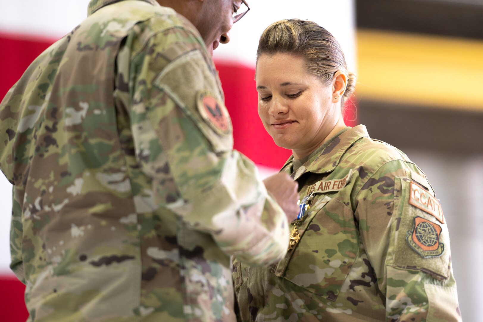An Air Force leader pins a medal on an airman's uniform.