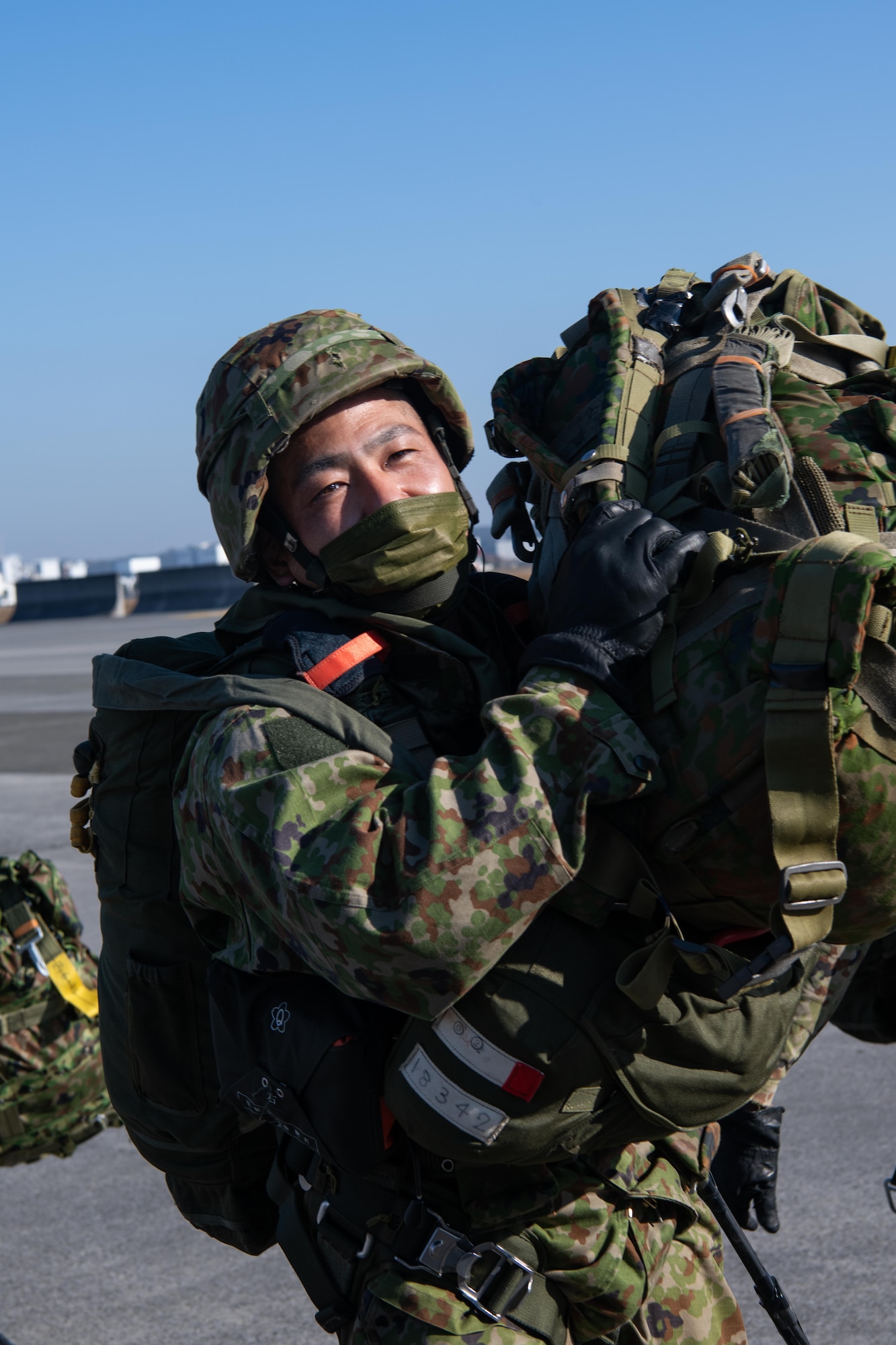 A Japan Ground Self-Defense Force soldier assigned to the 1st Airborne Brigade carries his gear to a 36th Airlift Squadron C-130J Super Hercules prior to a joint jump event starting at Yokota Air Base, Japan, Nov. 10, 2022.