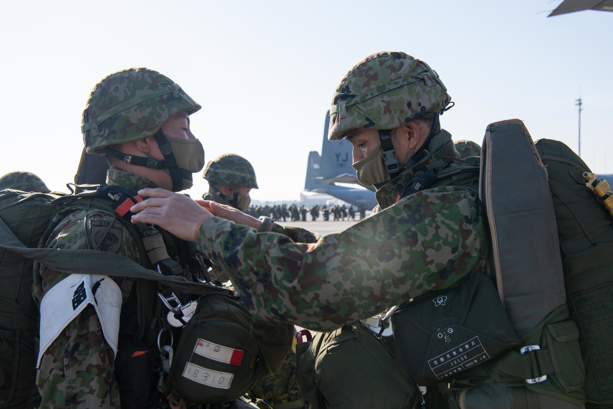 Japan Ground Self-Defense Force soldier performs an equipment check on another soldier prior to boarding a 36th Airlift Squadron C-130J Super Hercules for a joint jump event starting at Yokota Air Base, Japan, Nov. 10, 2022.