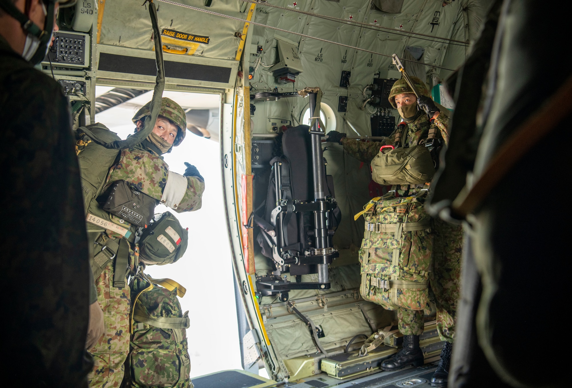 A Japan Ground Self-Defense Force paratrooper assigned to the 1st Airborne Brigade points out of the open paratroop of a 36th Airlift Squadron C-130J Hercules before static line jumps over Narashino drop zone, Chiba, Japan, Nov. 10, 2022.