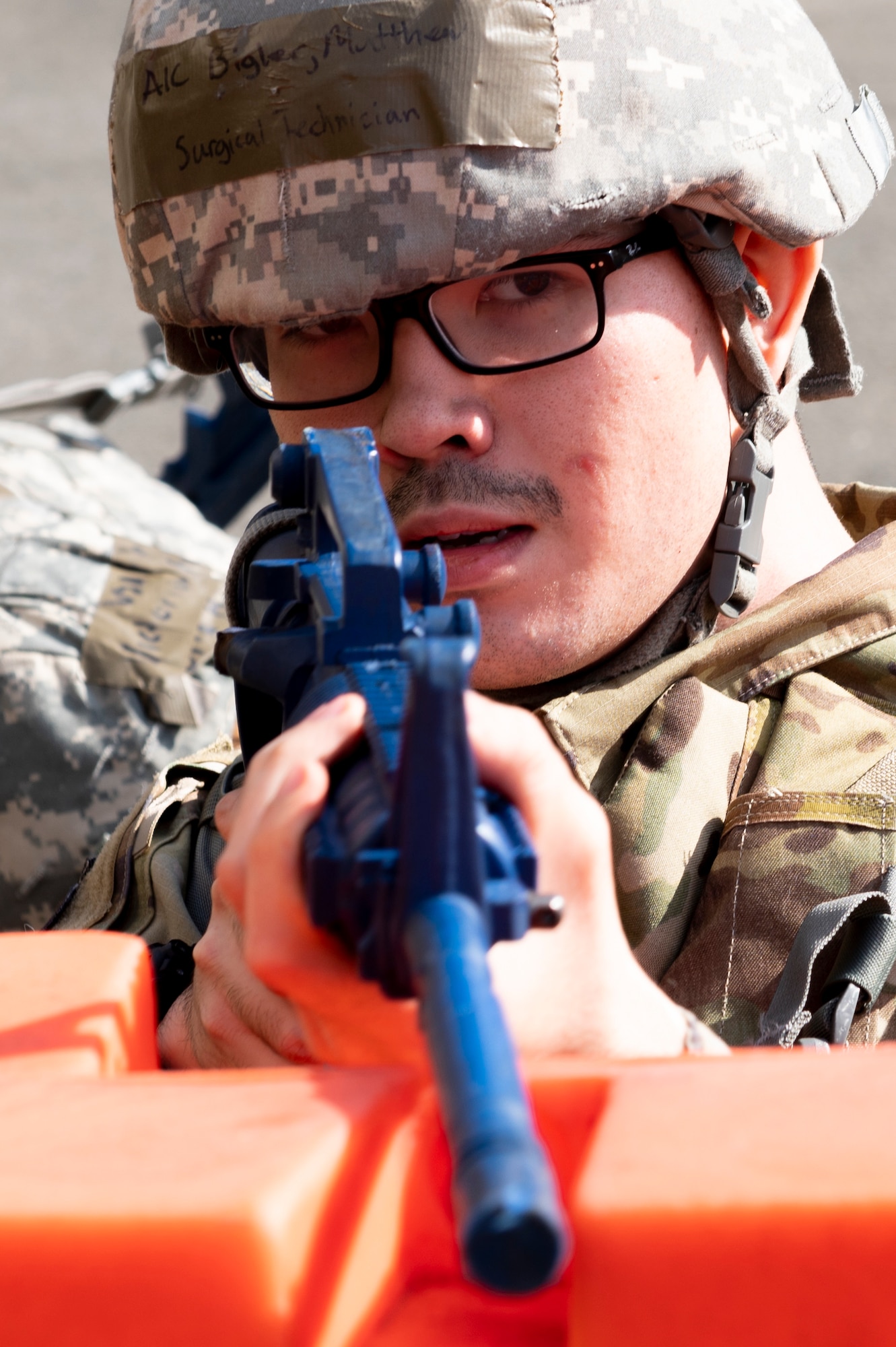 A medical airman points a simulated M-16 at the camera
