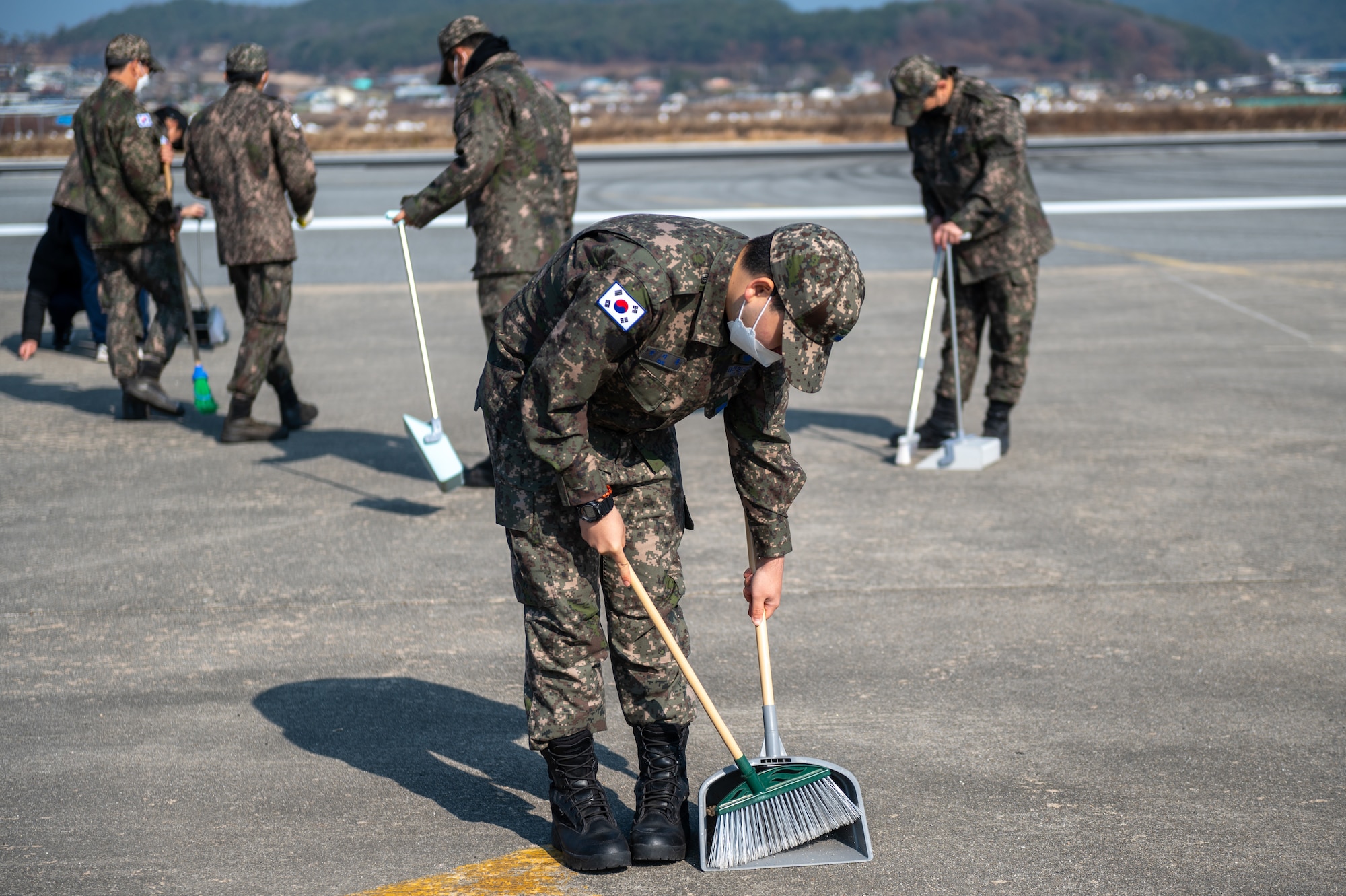 Republic of Korea Air Force members clear the area of debris, also known as foreign object disposal (FOD), at an emergency landing strip as part of a combined training event involving USAF and Republic of Korea Air Force partners