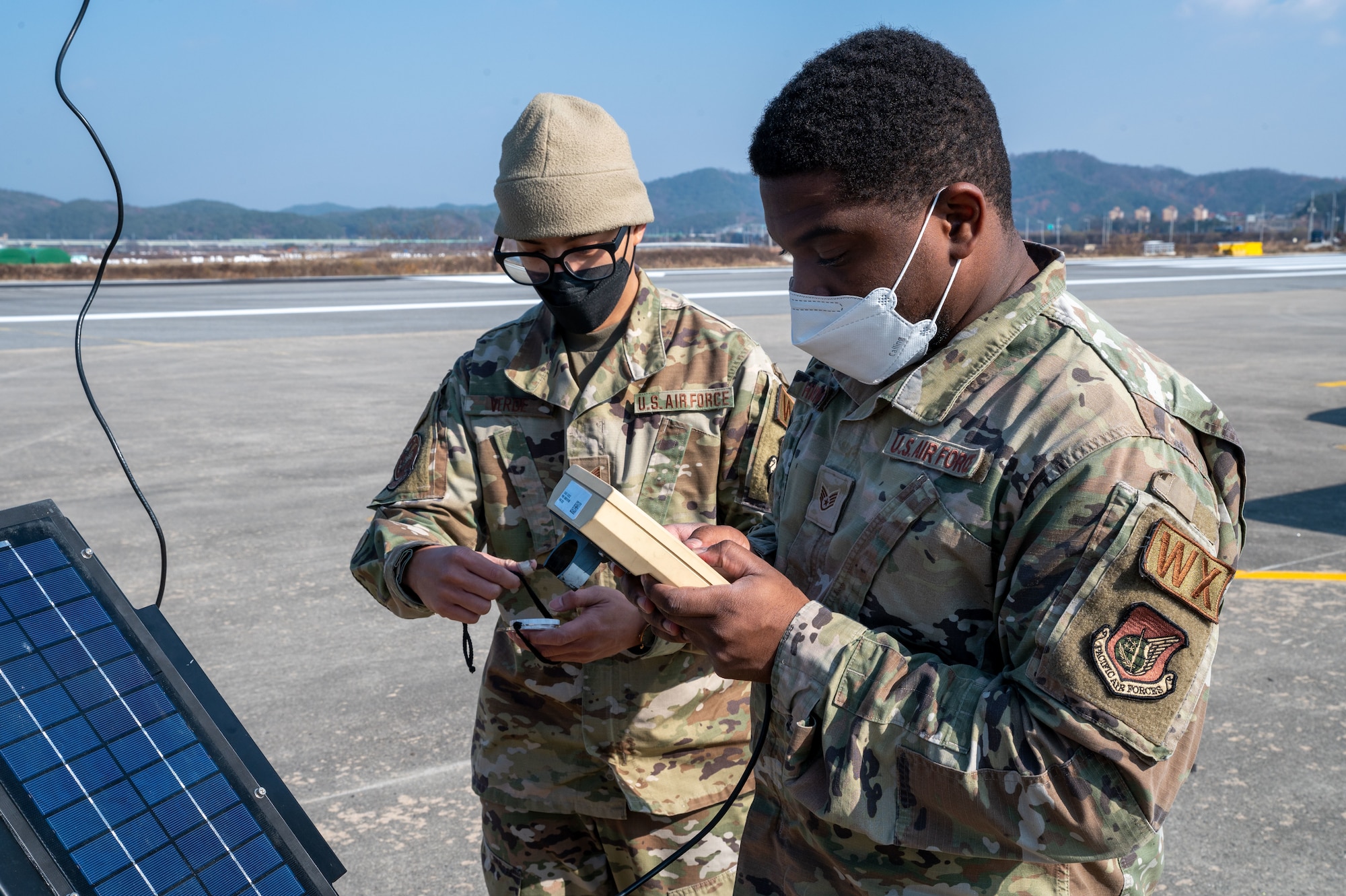 U.S. Air Force Staff Sgts. Andrew Verde and Jamal Hickmon, 51st Operational Support Squadron weather specialists, use a TMQ-53 tactical meteorological observing system handheld display to gather data from the system’s sensor during a low approach training event on an emergency landing strip