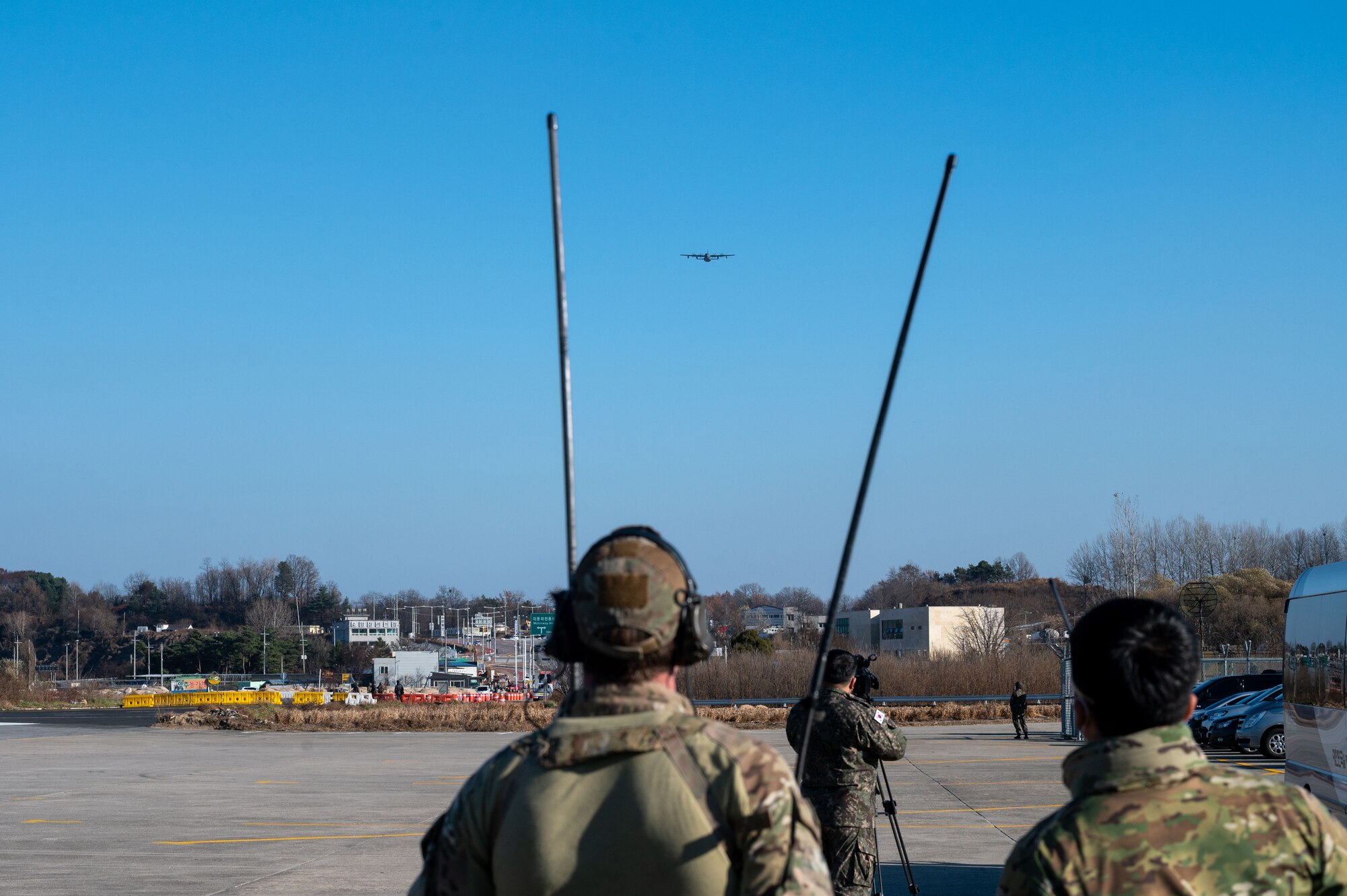 U.S. Air Force Special Operations Command Korea members communicate with an incoming A USAF MC-130J Commando II during a low approach emergency landing training
