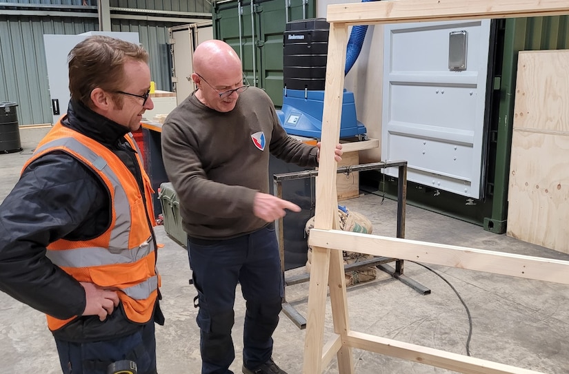 Antony Phoenix (right), the preservation team lead at Zutendaal Army Prepositioned Stocks-2 worksite, discusses a work project with one of his team members, carpenter Jurgen Van Hees. Phoenix is responsible for a team of six personnel, to include a carpenter. Their mission is to ensure all APS-2 equipment is preserved properly, in accordance with Army guidelines and regulations. (U.S. Army courtesy photo)