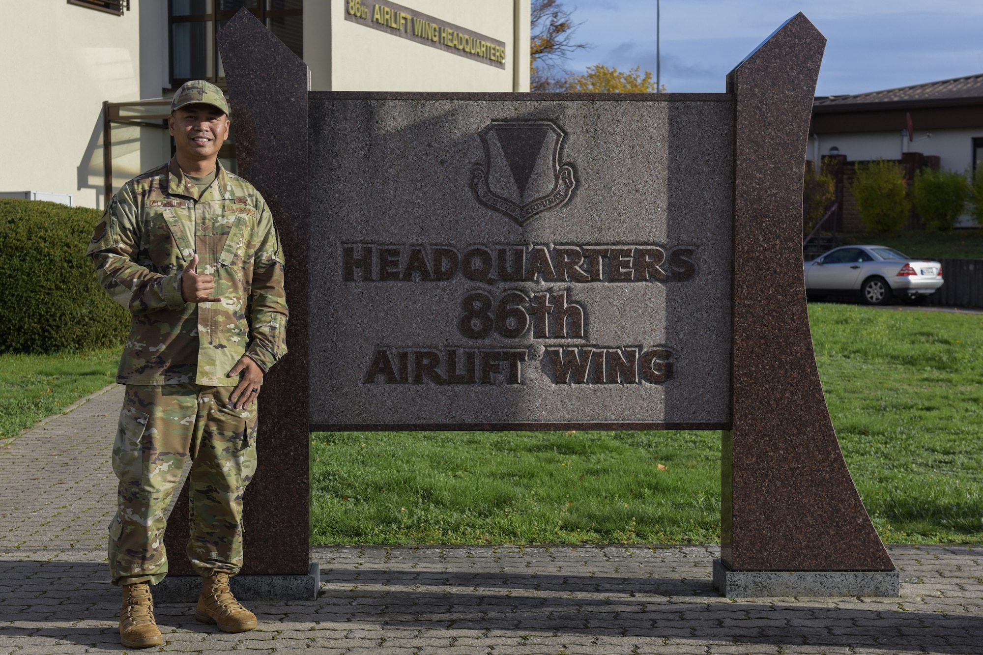 Man stands next to a sign and smiles for a picture