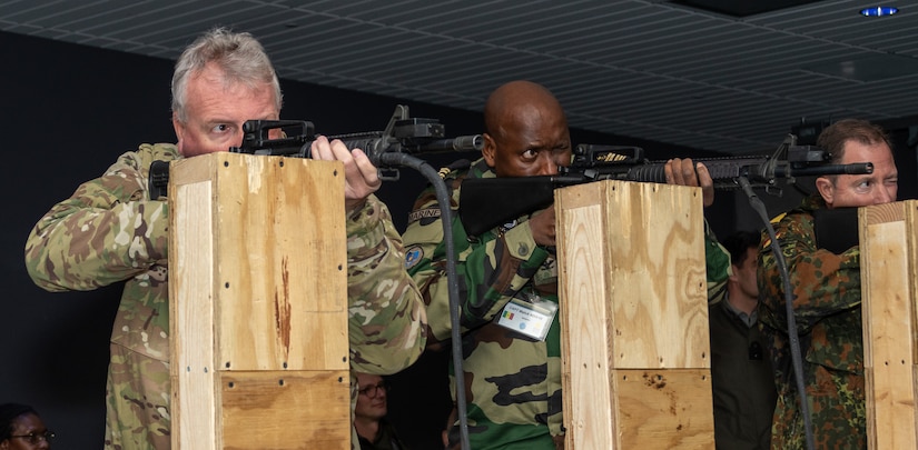 Attachés Brig. Gen. Michael Shapland, of New Zealand; Capt. Malick Ndiaye, of Senegal; and Rear Adm. Axel Ristau, of Germany, fire at targets on a range simulator at Fort Indiantown Gap’s Training Support Center Nov. 16 during Defense Intelligence Agency’s Fall 2022 Operations Orientation Program tour of Pennsylvania National Guard facilities here. (Pennsylvania National Guard photo by Wayne V. Hall)