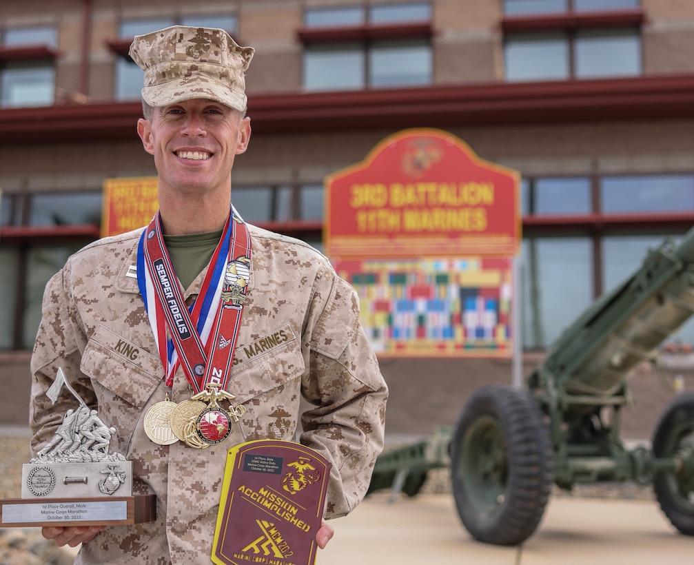 U.S. Marine Capt. Kyle King, the assistant operations officer with 3rd Battalion, 11th Marine Regiment, 1st Marine Division, poses for a photo with his awards from the 47th Annual Marine Corps Marathon at Marine Corps Air Ground Combat Center Twentynine Palms, California, Nov. 8, 2022. King is the first active-duty Marine to win the Marine Corps Marathon since 1983. The Marine Corps Marathon promotes physical fitness, generates community goodwill, and showcases the organizational skills of the Marine Corps.