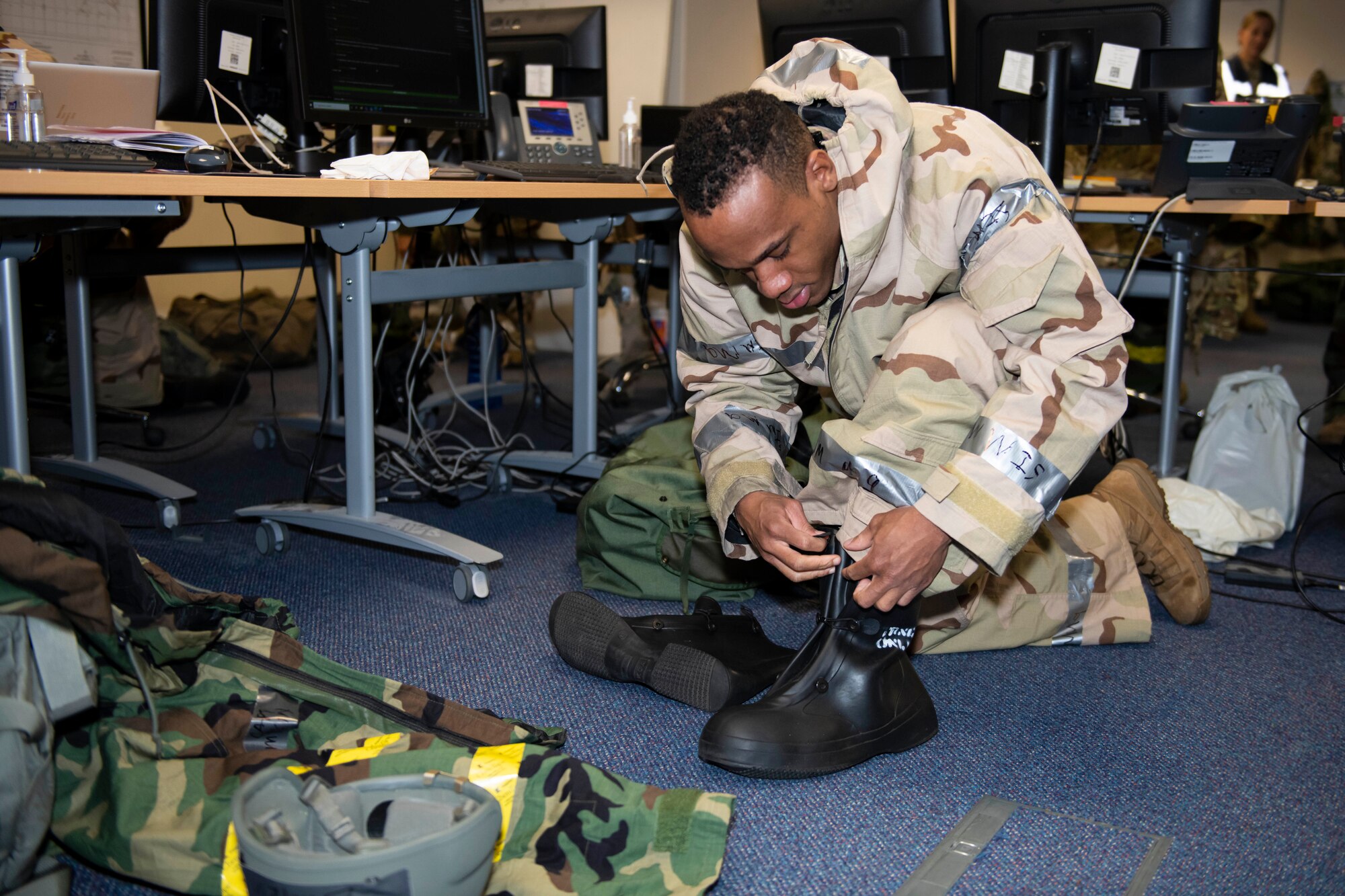 A member of the Emergency Operations Center dons their Mission Oriented Protective Posture gear during an exercise at RAF Alconbury, England, Nov. 17, 2022. The EOC is the command and control hub for emergency operations on base. Airmen across the 501st Combat Support Wing took part in a readiness exercise to test various capabilities, identify areas for improvement and strengthen operations. (U.S. Air Force photo by Senior Airman Jennifer Zima)