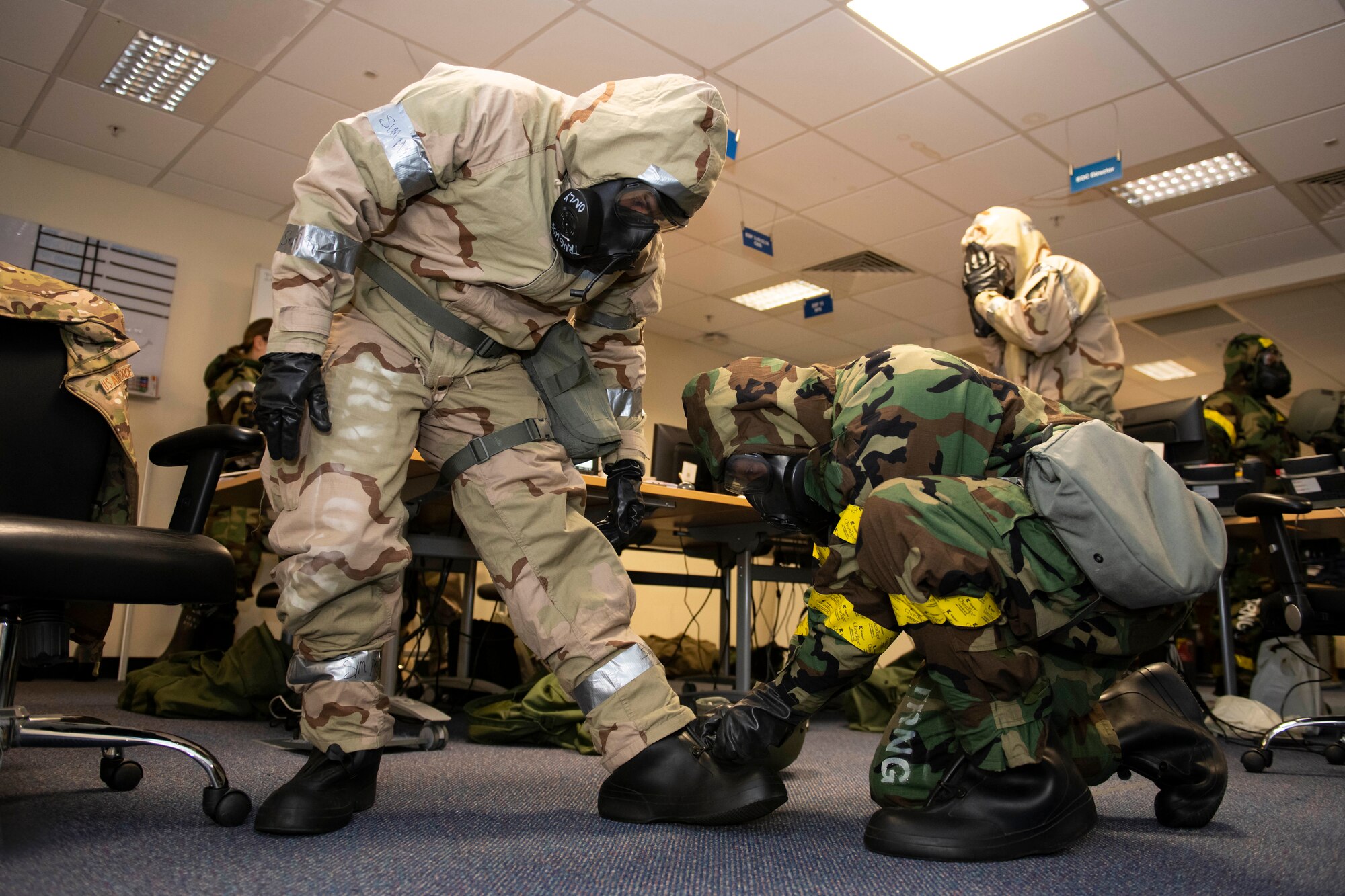 A member of the Emergency Operations Center assists a fellow Airman with their Mission Oriented Protective Posture gear during an exercise at RAF Alconbury, England, Nov. 17, 2022. The EOC is the command and control hub for emergency operations on base. Airmen across the 501st Combat Support Wing took part in a readiness exercise to test various capabilities, identify areas for improvement and strengthen operations. (U.S. Air Force photo by Senior Airman Jennifer Zima)