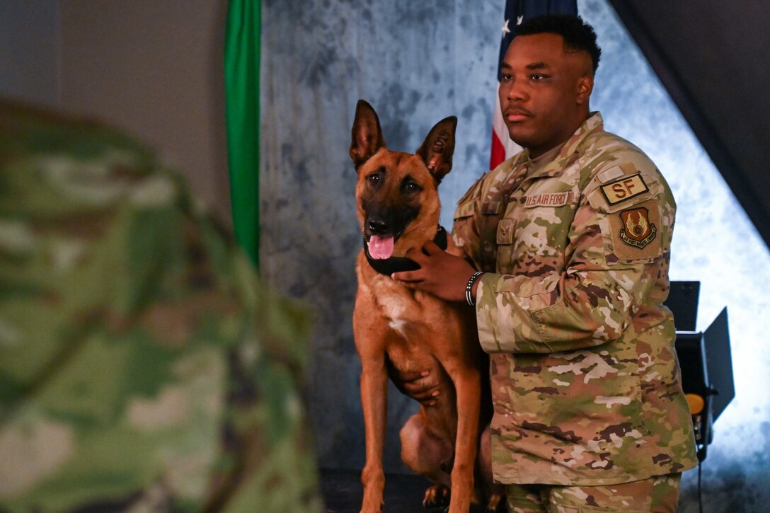 An airman holds a dog as they pose for a picture.