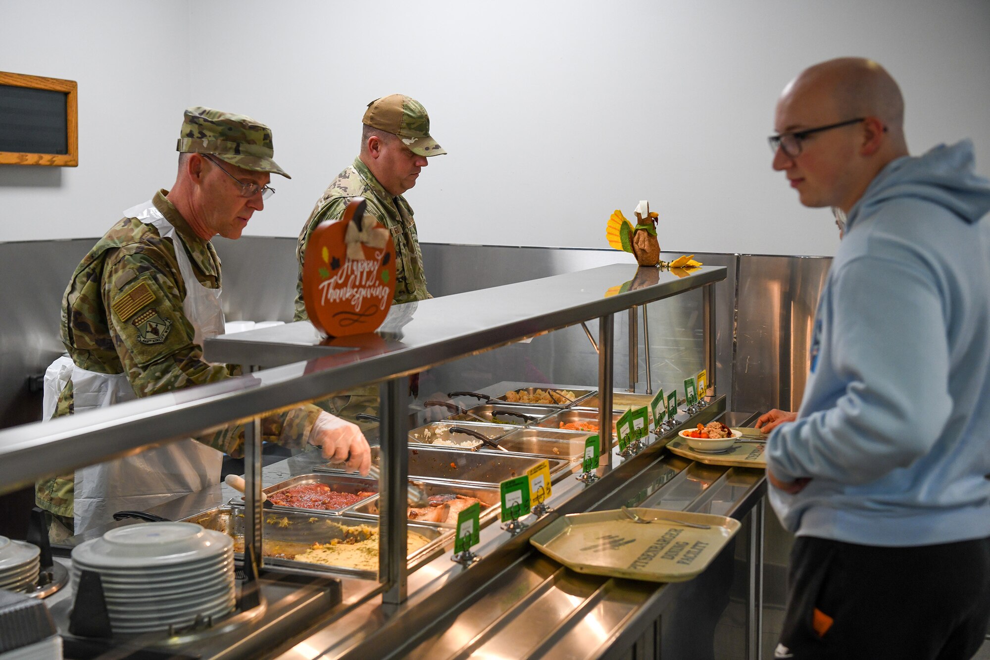Chief Master Sgt. Christopher Williams., 445th Airlift Wing command chief, serves lunch alongside Staff Sgt. Brian Snell, 445th Force Support Squadron services flight, to Airman at the Pitsenbarger Dining Facility, Wright-Patterson Air Force Base, Ohio, Nov 6, 2022. Commanders, first sergeants and chiefs serve Airmen at the dining facility during November unit training assemblies to show their appreciation for their service.