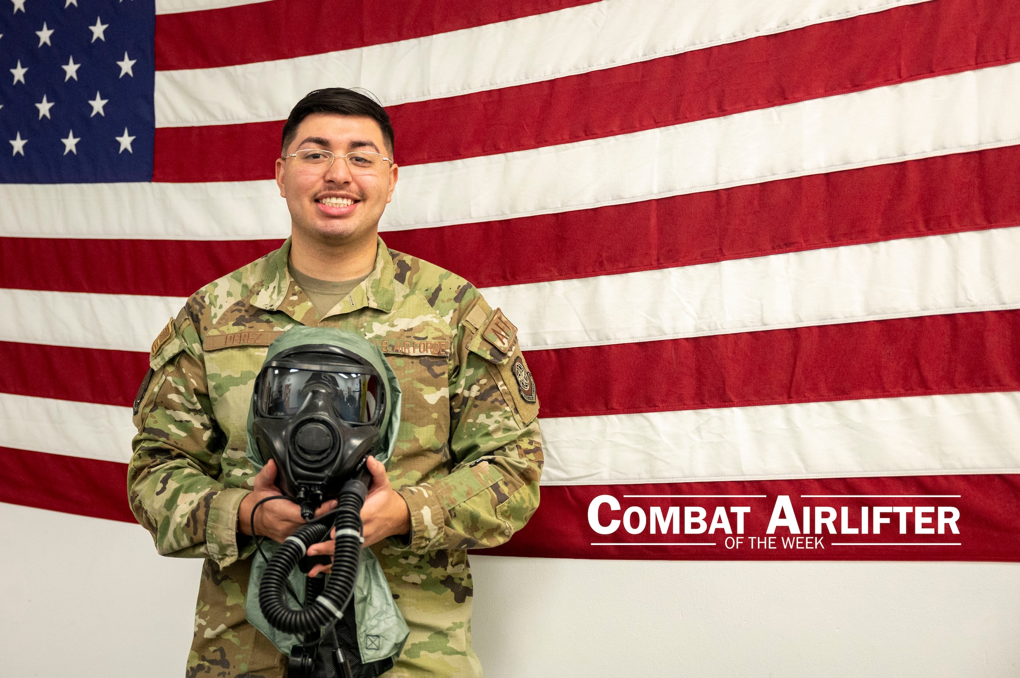 A man in uniform poses for a photo in front of an American flag