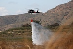 A U.S. Army UH-60M Black Hawk helicopter flown by Soldiers from the 1st Assault Helicopter Battalion, 140th Aviation Regiment, California Army National Guard, drops a bucket of water during aerial wildland firefighting training with the California Department of Forestry and Fire Protection, March 19, 2022, in Silverado, California. Cal Guard and CAL FIRE have a decades-long partnership for battling California’s larger wildfires.