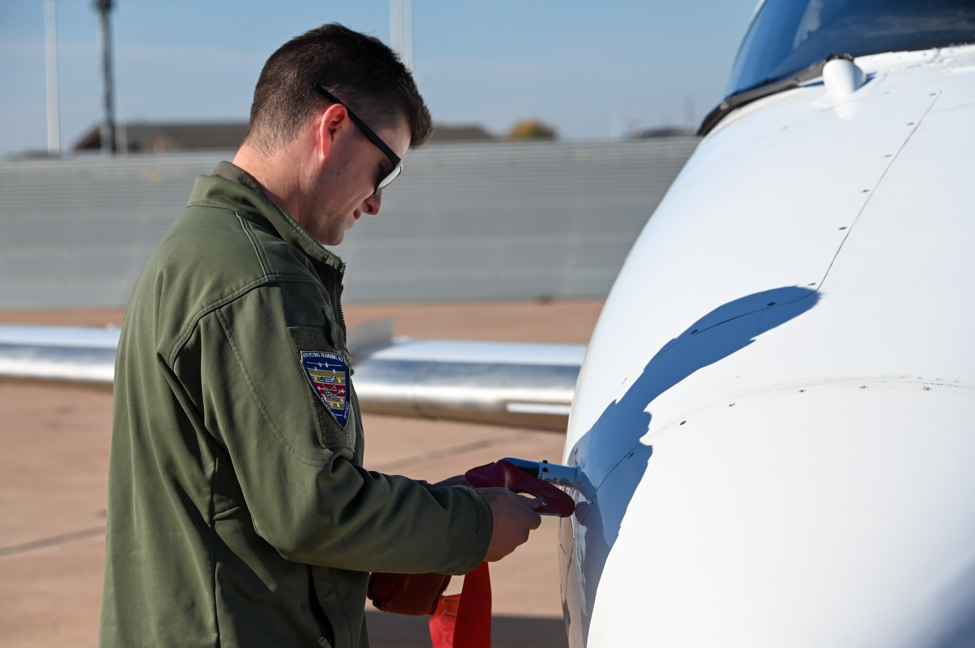 U.S. Air Force Capt. Brendan Bailey, 48th Flying Training Squadron instructor pilot, attaches a pitot cover on a T-1 Jayhawk at Altus Air Force Base (AFB), Oklahoma, Nov. 15, 2022. Bailey was able to fly on the KC-46 Pegasus and watch in-flight refueling while at Altus AFB. (U.S. Air Force photo by Senior Airman Kayla Christenson)