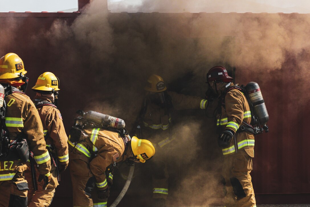 Firefighters with the Combat Center Fire Department conduct a burn box exercise at Marine Corps Air Ground Combat Center, Twentynine Palms, California, Sept. 26, 2022. Firefighters conduct burn box drills to hone their skills in a controlled interior and high intensity heat environment. (U.S. Marine Corps Photo by Lance Cpl. Christy Yost)