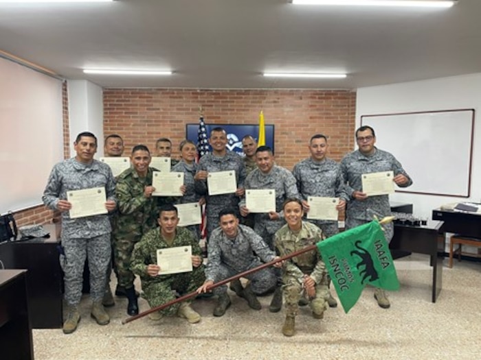 Service members posing for photo with flag