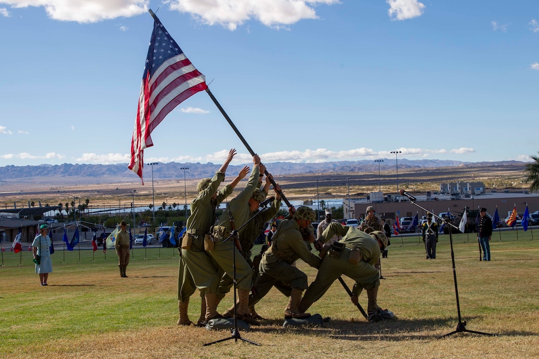 U.S. Marines with Headquarters Battalion, Marine Corps Air Ground Combat Center (MCAGCC), reenact the WWII flag raising atop Mount Suribachi on Iwo Jima during the Marine Corps historical uniform pageant at MCAGCC, Twentynine Palms, California, Nov. 9, 2022. The event included a historical uniform pageant and the traditional cake cutting ceremony in honor of the 247th Marine Corps birthday. (U.S. Marine Corps photo by Lance Cpl. Jacquilyn Davis)