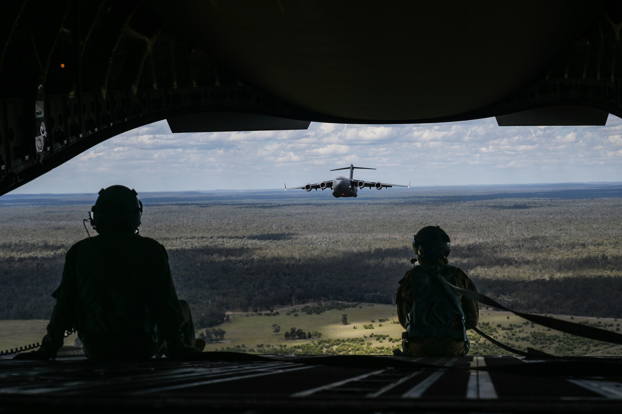 Royal Australian Air Force Corporal Shawn Harding, No. 36 Squadron loadmaster, and U.S. Air Force Senior Airman Jo Besse, 535th Airlift Squadron loadmaster, sit on the ramp of a RAAF C-17 Globemaster III in a two-ship formation flight during Exercise Global Dexterity in the skies over Queensland, Nov. 14, 2022. Exercise Global Dexterity 2022 is being conducted at RAAF Base Amberley, and is designed to help develop the bilateral tactical airlift and airdrop capabilities of the United States Air Force (USAF) and the Royal Australian Air Force (RAAF). Both the United States and Australia rely on the C-17A to provide strategic and tactical airlift across the Indo-Pacific region, with its ability to provide short-notice and time-critical airlift support making it essential during humanitarian assistance and disaster relief operations. (U.S. Air Force photo by Staff Sgt. Alan Ricker)