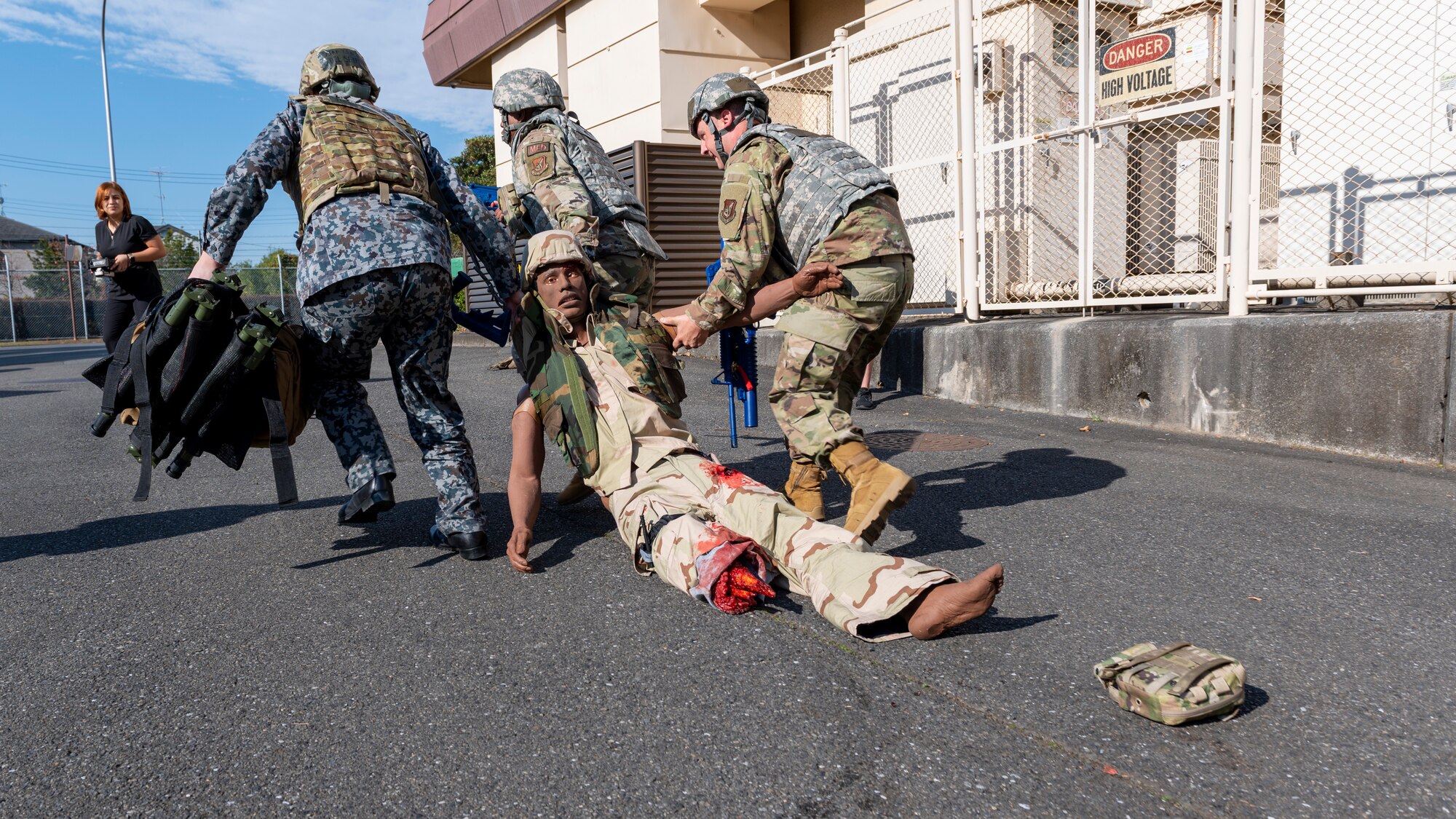 Three medical Airmen drag a medical training dummy to safety
