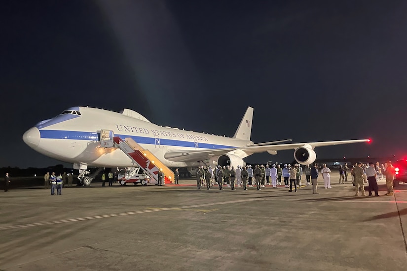 A plane bearing the words United States of America sits on a tarmac as people mill about.