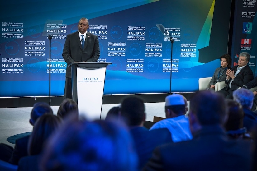 A man dressed in a business suit stands behind a dias.