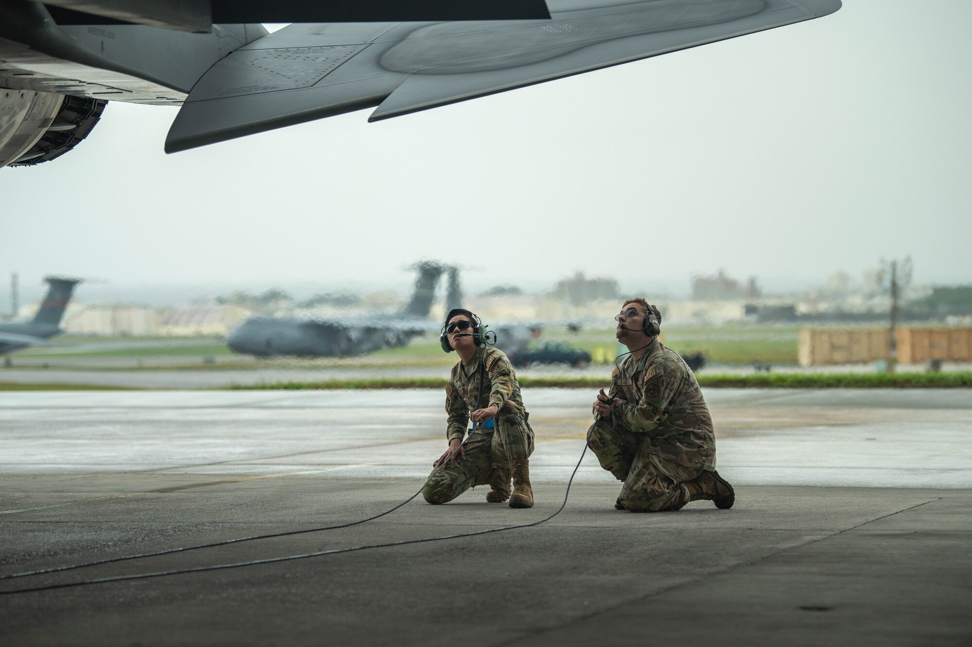 Crew chief and maintainer crouch below F-15.