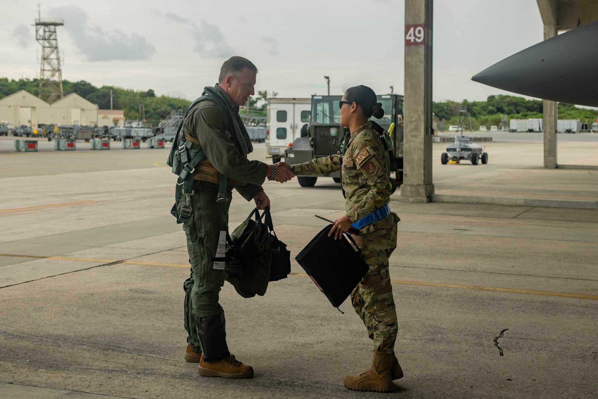 Pilot shales hands with a crew chief in front of a jet.