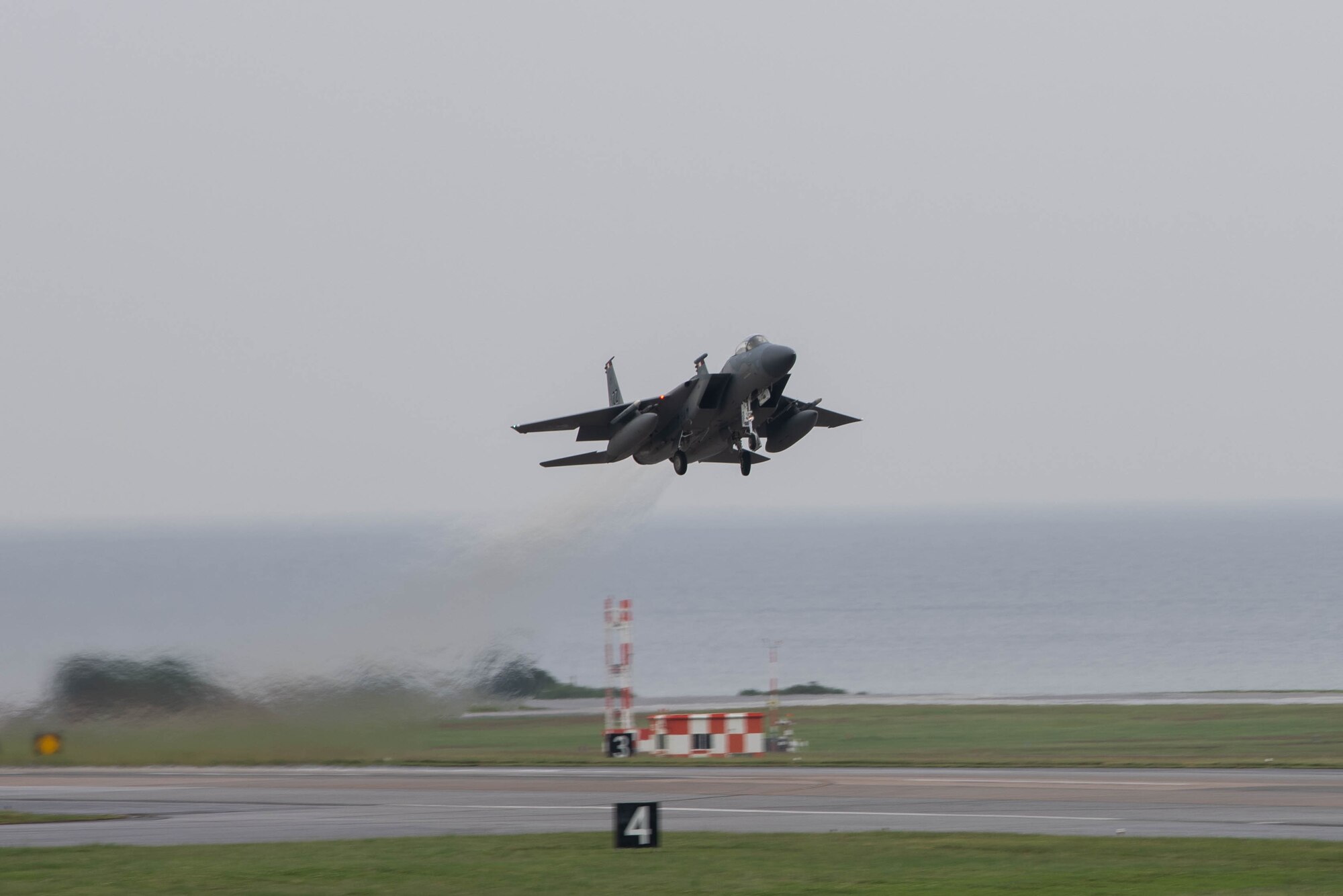 Jet flies over runway.