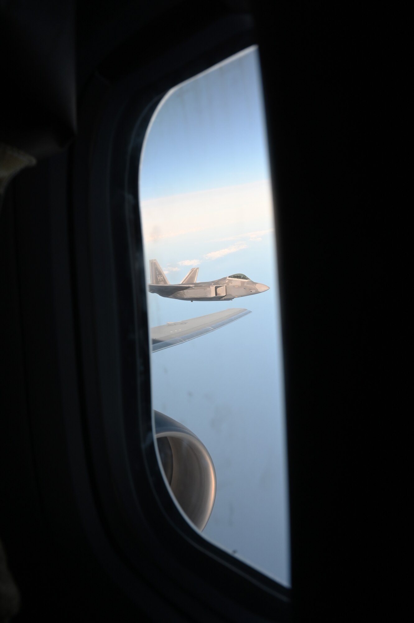 An F-22 Raptor flies off the wingtip of a KC-46A Pegasus.