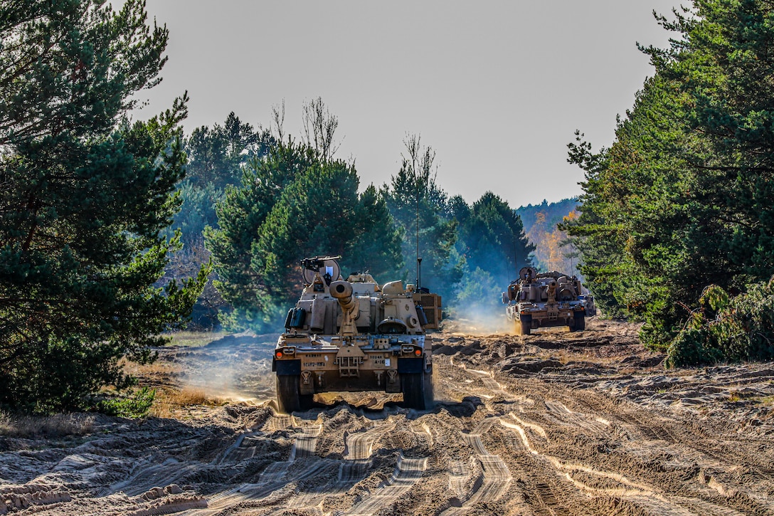 Several tanks roll down the road during an exercise.