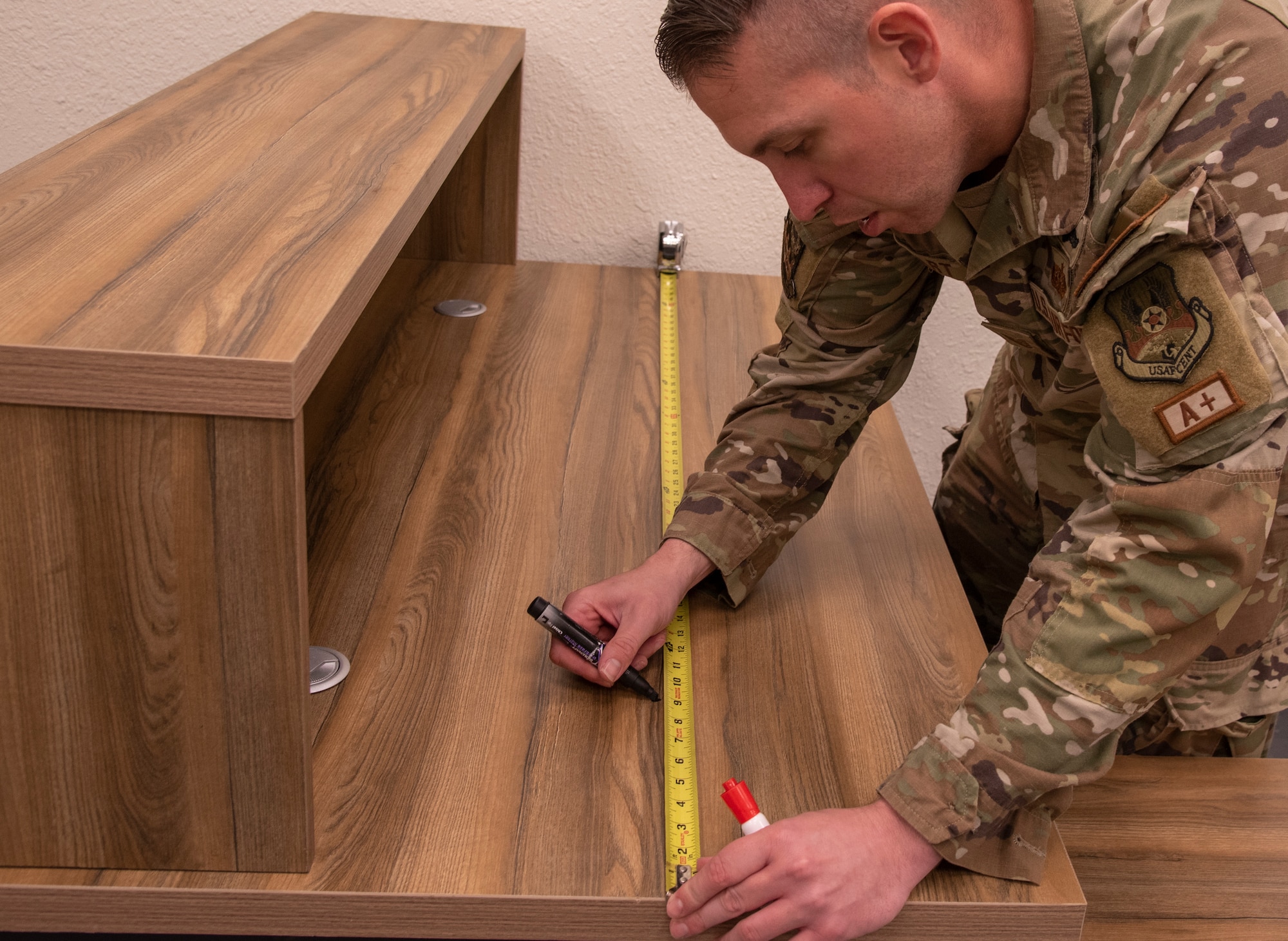 U.S. Air Force Tech. Sgt. Andrew Hart, 332d Expeditionary Communications Squadron, measures a desk to create tempest diagrams at an undisclosed location, Southwest Asia, Nov. 3, 2022. These diagrams determine where network devices will be placed in order to prevent secure and non-secure devices from connecting. (U.S. Air Force photo by: Tech. Sgt. Jim Bentley)