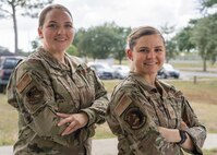Two Airmen stand with arms crossed while posing for a photo.