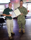 NSWC IHD Commanding Officer Capt. Eric Correll presents former NSWC IHD employee Ralph Lee Gootee Jr. with the Department of the Navy Meritorious Civilian Service Award, the third highest Navy civilian award, Nov. 10.