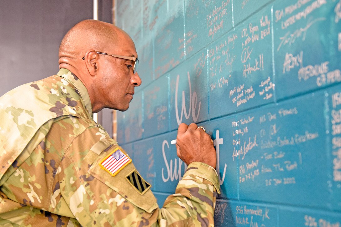 A soldier writes on a wall.