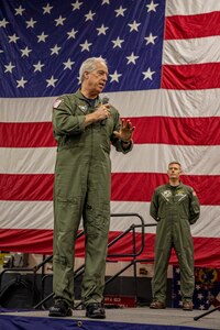 Rear Adm. Meier talking on stage with American Flag in background