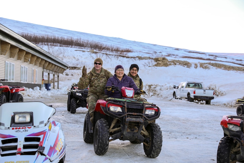 Alaska Army National Guard Staff Sgt. Eddie Jones, left, a Bethel recruiter with the Recruiting and Retention Battalion, and Private 1st Class Jared Alirkar, a transportation management coordinator with the 49th Personnel Detachment (Theater Gateway), catch a ride on the back of a four-wheeler from the local school to the airfield during Operation Santa Claus in Scammon Bay, Nov. 16, 2022. Operation Santa Claus is the Alaska National Guard’s yearly community relations and support program that provides gifts to children in remote communities across the state. In partnership with the Salvation Army and with more than a dozen volunteers, the program delivered 1,780 pounds of gifts, backpacks, hygiene supplies, and books to 325 children in Scammon Bay. (Alaska National Guard photo by 1st Lt. Balinda O’Neal)