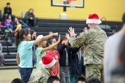 Alaska Army National Guard Staff Sgt. Eddie Jones, left, a Bethel recruiter with the Recruiting and Retention Battalion, shares holiday cheer with local children during Operation Santa Claus in Scammon Bay, Nov. 16, 2022. Operation Santa Claus is the Alaska National Guard’s yearly community relations and support program that provides gifts to children in remote communities across the state. In partnership with the Salvation Army and with more than a dozen volunteers, the program delivered 1,780 pounds of gifts, backpacks, hygiene supplies, and books to 325 children in Scammon Bay. (Alaska National Guard photo by 1st Lt. Balinda O’Neal)