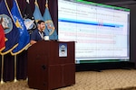 Man standing at podium presenting slide.