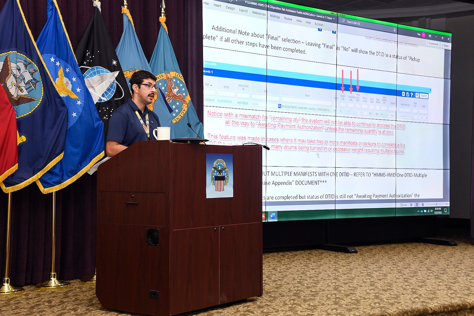 Man standing at podium presenting slide.