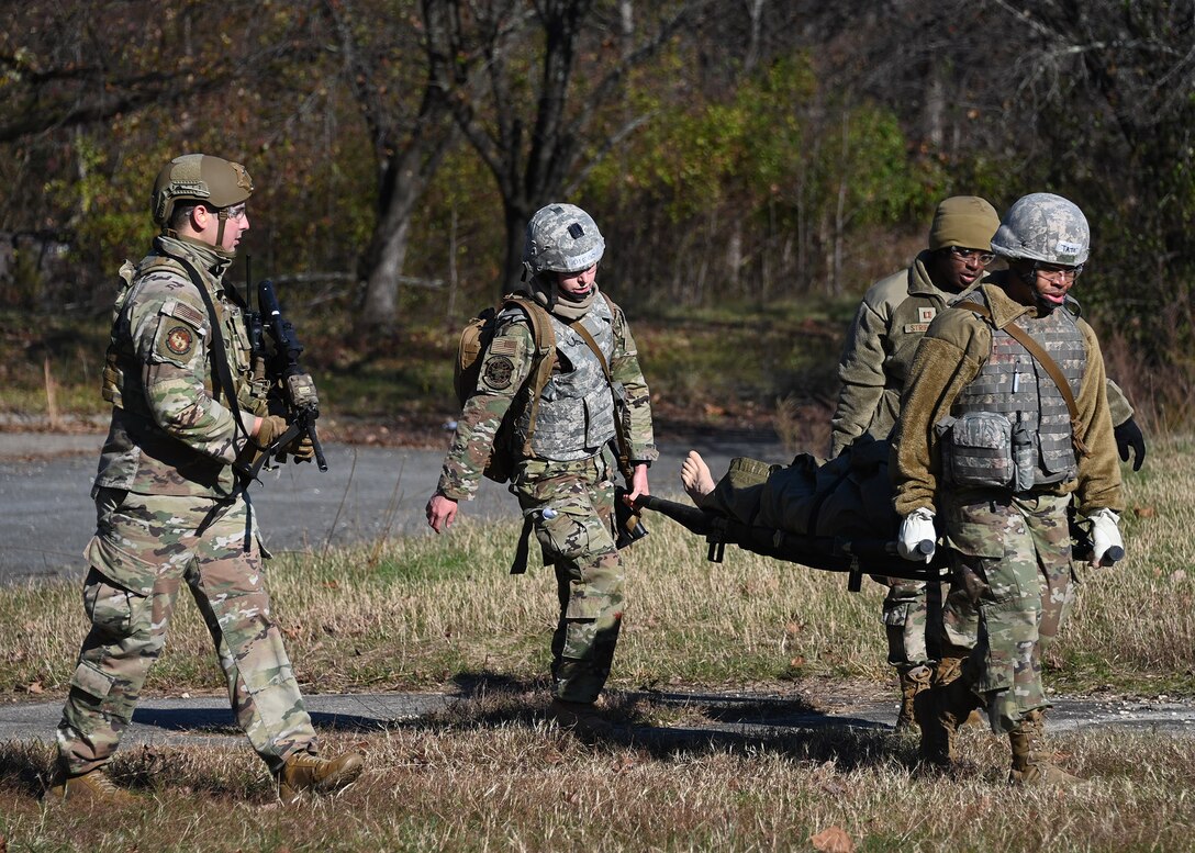 Airmen carry a victim towards a helicopter during Tactical Combat Casualty Care training at Joint Base Andrews, Md., Nov. 18, 2022. The TCCC Training consisted of moving towards injured victims, then performing proper emergency care methods and evacuation by helicopter. (U.S. Air Force photo by Airman 1st Class Austin Pate)